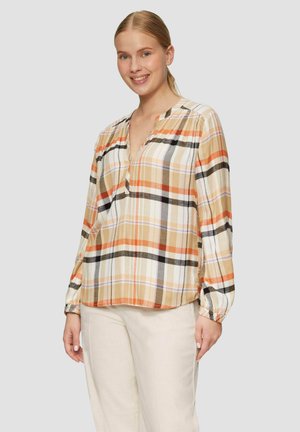 Blouse à carreaux dans des tons chauds d'orange, de marron et de blanc. Dispose d'un col en V, de manches longues avec des poignets élastiques et d'un tissu léger.