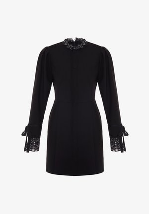 Musta mekko, jossa on pitkät hihat, nappi etuosa ja röyhelökaulus. Hihansuissa on pitsikerros, jossa on pilkku kuvio ja nauha yksityiskohtia.