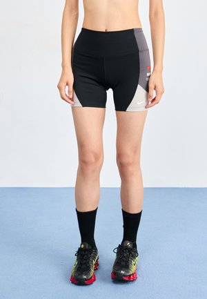 Zwarte sportshorts met grijze accenten en het Nike-logo; gecombineerd met zwarte sokken en kleurrijke sportschoenen. Verstelbaar ontwerp van de tailleband.
