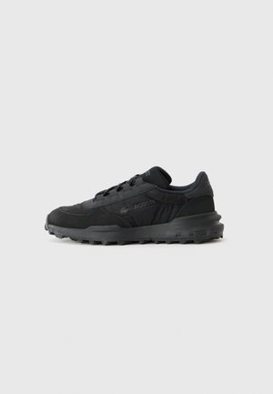 Zapatillas deportivas negras que combinan materiales lisos y texturizados, con un diseño bajo, cordones y suela de goma duradera.