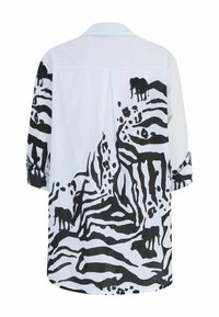 White shirt featuring a black abstract animal pattern, including elephants and other shapes, with a relaxed fit and cuffed sleeves.