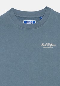 Μπλε φούτερ με στρογγυλή λαιμόκοψη, με την επιγραφή "Jack & Jones Archive Selection" τυπωμένη στο επάνω αριστερό μέρος του στήθους και ετικέτα μάρκας μέσα στον γιακά.