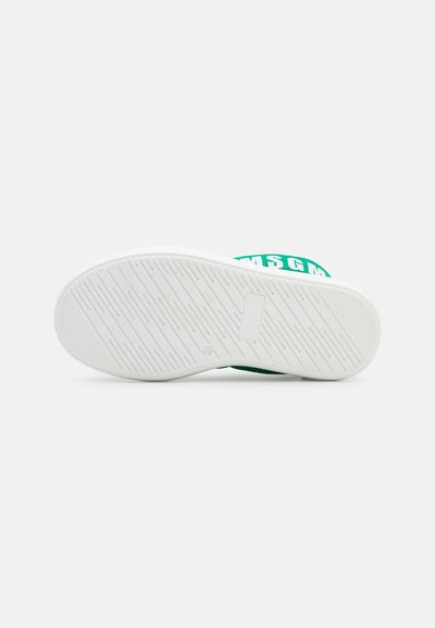 Sapatilhas verdes e brancas com uma sola de borracha texturada, apresentando uma ampla correia verde com texto do logótipo branco na parte superior.