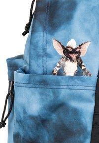 Borsa blu con motivo tie-dye e un personaggio Gremlin ricamato sulla tasca anteriore. Materiale in tessuto testurizzato e resistente.