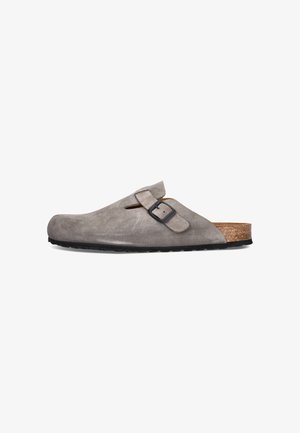 Grauer Wildleder-Slipper-Clog mit verstellbarem Schnallenriemen, Korkfußbett und schwarzer strukturierter Sohle, seitlich auf weißem Hintergrund gezeigt.