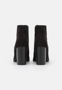 Svarta mocka anklarstövlar med rund tå och staplad cylindrisk klack. Har en slät ovandel och subtila sömdetaljer.