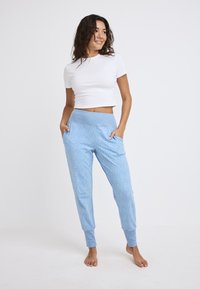 Lichtblauwe joggers met een zachte textuur, voorzien van een brede elastische tailleband en twee zijzakken, versierd met kleine, subtiele stippenpatronen.