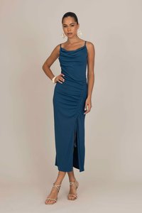 Robe maxi en sarcelle à côtes avec encolure bénitier, fronces sur un côté et une fente haute jusqu'à la cuisse. Associée à des sandales à lanières et à des boucles d'oreilles accrocheuses.