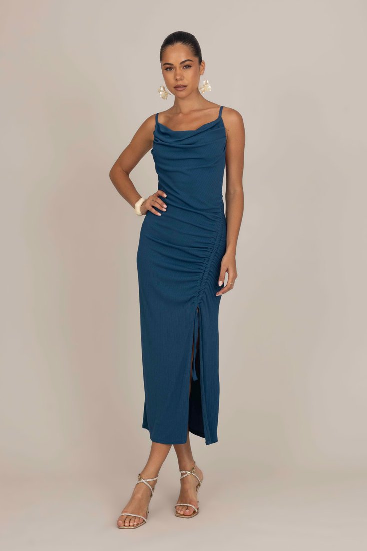 Robe maxi en sarcelle à côtes avec encolure bénitier, fronces sur un côté et une fente haute jusqu'à la cuisse. Associée à des sandales à lanières et à des boucles d'oreilles accrocheuses.