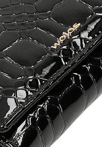 Zwarte gepatineerde leren portemonnee met een textuur van krokodillenpatroon en een goudkleurig logo-accent. Compact ontwerp met een gladde afwerking.