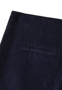 Tissu en velours côtelé bleu marine avec des rainures verticales, doté d'une poche arrière unique avec une ouverture horizontale. Texture lisse.