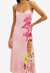 Vestido slip con estampado floral en suave tela rosa, que presenta orquídeas vibrantes y jarrones decorativos con acentos amarillos y patrones. Tirantes ajustables.