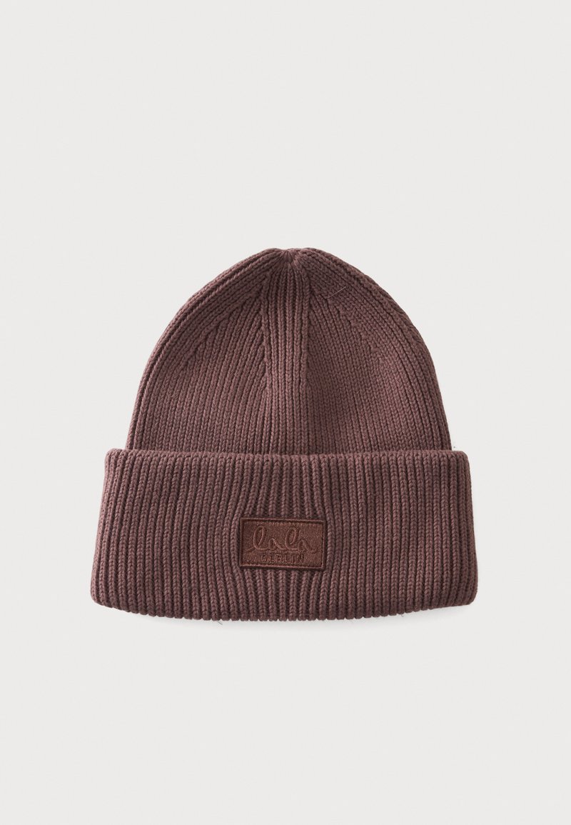 Bonnet en tricot côtelé marron avec revers plié et une étiquette rectangulaire à l'avant sur fond uni.