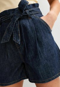 Denim shorts in dark blue with a high waistband, tied belt detail, side pockets, and contrast stitching for added texture.