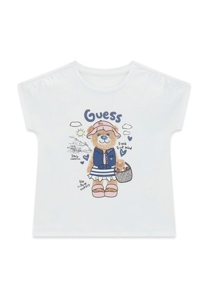 Witte kinder-T-shirt met een beer die een hoed, vest, gestreepte rok en sandalen draagt, een mand vasthoudt, en tekst met onder andere "Guess" en "Italie vakantie".