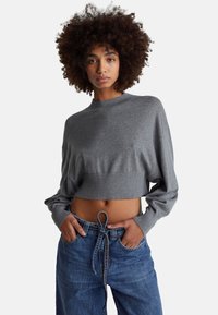 Szary krótki sweter z długimi rękawami i prążkowanym dekoltem, zestawiony z niebieskimi jeansami z wysokim stanem, wyposażonymi w kieszenie i sznurek do wiązania.