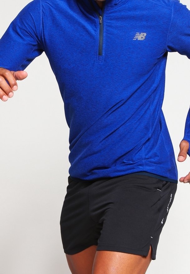 Blå långärmad atletisk topp med kvart dragkedja och svarta shorts. Har en subtil logo och fukttransporterande tyg för komfort.