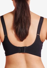 Svart sömlös bh med justerbara axelband, texturerat ribbat material och ett spänne bak med delikata spetsdetaljer.