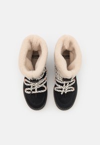 Bottines noires avec une doublure en fausse fourrure beige douce, des lacets mouchetés et des semelles en caoutchouc. Caractéristiques d'un design robuste adapté aux climats froids.