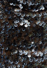 Tissu noir densément recouvert de petits sequins ronds brillants reflétant la lumière en tons argentés et foncés.