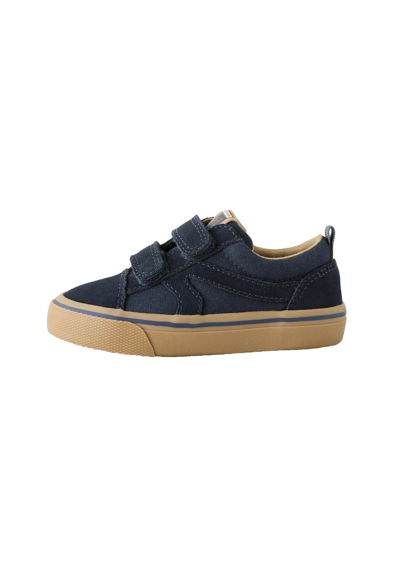 Chaussure en toile bleu marine avec deux bandes Velcro, semelle en caoutchouc beige et bout arrondi. Présente des accents de couture et une petite languette au talon.