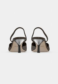 Chaussures à talons hauts en daim marron avec un bout arrondi, un dos ouvert et un talon métallique. Dotées d'une fine bride à la cheville pour un meilleur maintien.