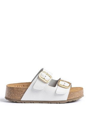 Witte sandaal met open teen, twee gouden gespen, kurken zool en een bruin voetbed, zijaanzicht tegen een witte achtergrond.