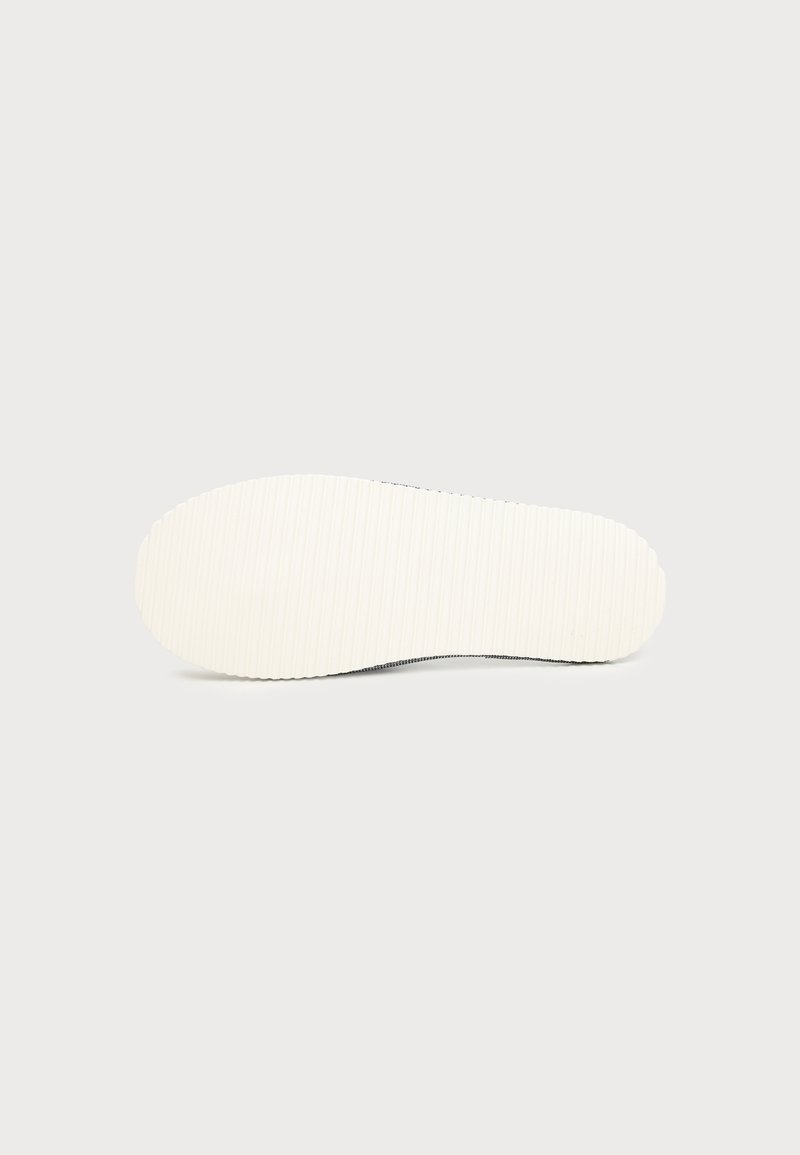 Flat white rubber shoe sole with a subtle striped texture, displayed against a plain light gray background.
