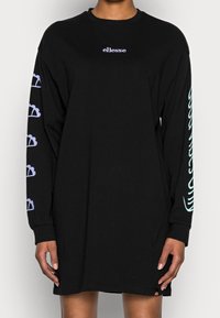 Robe noire à manches longues avec un petit logo blanc sur la poitrine et des graphismes violet clair sur les manches. Fabriquée en tissu de coton.