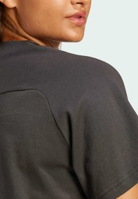 Camiseta de algodón gris oscuro con una textura suave, mangas cortas y un escote redondeado con un sutil detalle de costura en el hombro.