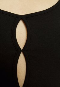 Top preto com um design ajustado, apresentando um recorte em forma de olho-chave no peito e uma textura canelada ao redor da gola.