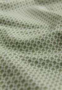 Material textil verde cu un model structurat, având un design geometric într-o nuanță mai deschisă pe un fundal estompat. Textură moale.