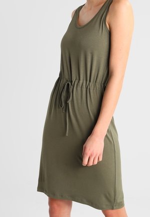 Robe sans manches vert olive longueur genou avec taille à cordon, portée par une personne avec le bras détendu le long du corps.