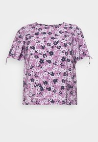 Blusa de manga corta con un patrón floral en rosa, lavanda y púrpura oscuro, ajuste relajado y escote redondo, sobre fondo blanco.