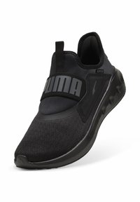 Scarpa sportiva nera senza lacci con tessuto testurizzato, suola spessa e fascia larga sulla parte superiore con il marchio "PUMA" in grigio.