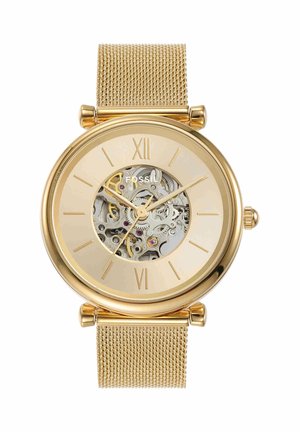 Montre-bracelet Fossil en or avec bracelet en maille, cadran squelette montrant les engrenages internes, chiffres romains à 12 et 6, aiguilles dorées des heures, minutes et secondes.