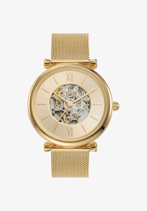 Montre-bracelet Fossil en or avec bracelet en maille, cadran squelette montrant les engrenages internes, chiffres romains à 12 et 6, aiguilles dorées des heures, minutes et secondes.