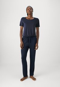Conjunto de loungewear en azul marino que incluye una camiseta de mangas cortas y pantalones con cinturilla elástica. Tejido suave con un corte relajado, sin patrones ni acentos visibles.