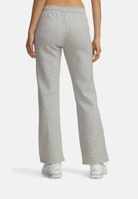 Grå, flagrende sweatpants med elastisk talje, blød tekstur og rå kanter. Sammen med hvide sports sneakers.