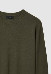 Olivgrüner Strickpullover mit Rundhalsausschnitt, aus strukturierter Stoffqualität und mit gerippten Kanten. Etikett trägt die Aufschrift "CALLIOPE", Größe L.
