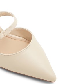 Sprettrundad creamfärgad läderlängd med en tunn ankelsnodd. Slen textur, minimalistisk design, med en mjuk beige inredning och sydda kanter.