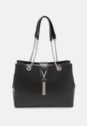 Musta nahkainen olkalaukku hopeisilla ketjusankareilla, litteä muotoilu, näyttävä "V"-koriste ja hapsuyksityiskohta hienovaraisella ketjuaskartelulla.