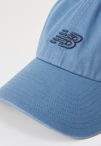 Casquette de baseball bleu clair avec une visière courbée cousue et un logo "NB" brodé en bleu foncé sur le panneau avant.