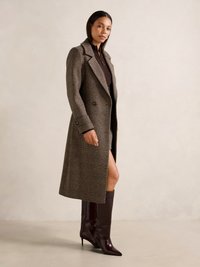 Cappotto lungo a quadri marroni con collo a rever, bottoni doppi, abbinato a stivali aderenti bordeaux al ginocchio. Texture lisce.