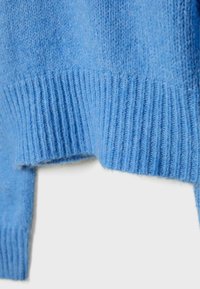 Hellblauer Strickpulloverabschnitt mit geripptem Saum. Weiche Textur, lockere Passform mit leicht kurz geschnittenem Design am unteren Ende.