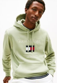 Felpa verde chiaro realizzata in misto cotone, con nome e logo del marchio ricamati, coulisse regolabile e tasca frontale.