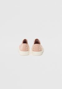 Scarpe in suede rosa con dettagli a pois bianchi sul tallone e una suola in gomma bianca. Design minimalista con forma arrotondata e texture morbida.