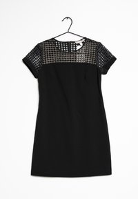 Svart klänning med en solid stoff kropp och en texturerad mesh-överdel med ett diamantmönster. Korta ärmar, rund halsringning och en dragkedjestängning på baksidan.
