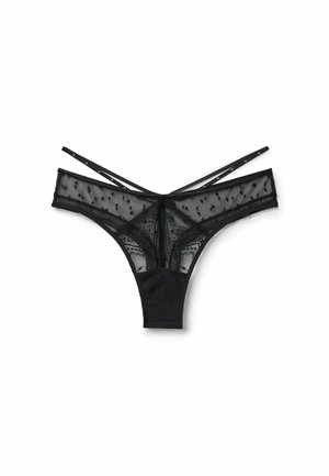 String en dentelle noire transparente avec motifs à pois, ceinture unie contrastante et fines lanières croisées à l'arrière.