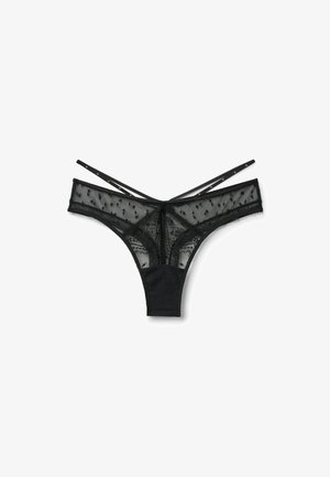 String en dentelle noire transparente avec motifs à pois, ceinture unie contrastante et fines lanières croisées à l'arrière.